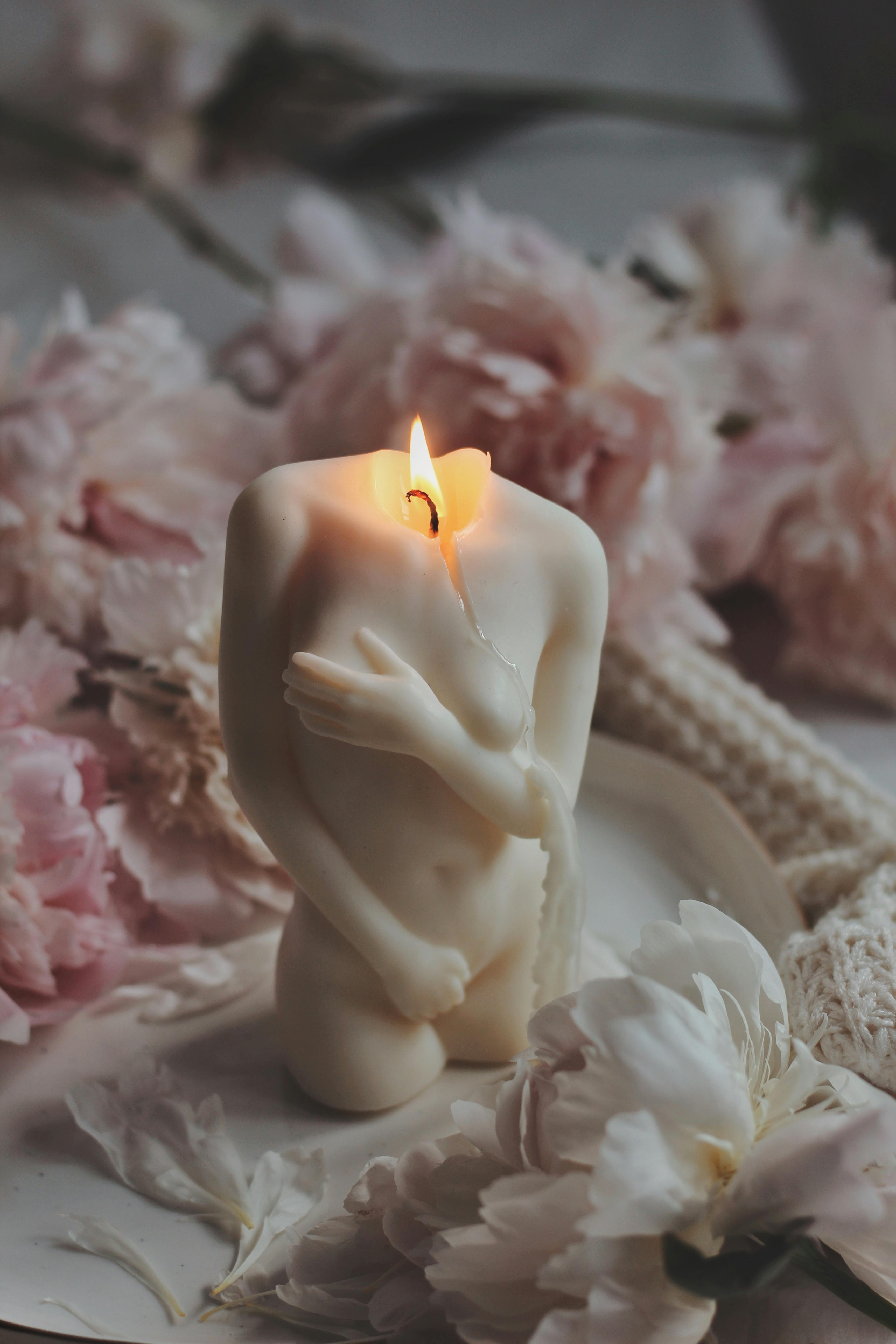 a human female figure candle, lit, wax dripping, embodying fire and sensuality